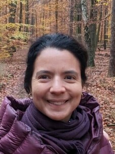 Bella Lake mit dunklen Haaren und lila Schal im herbstlichen Wald.